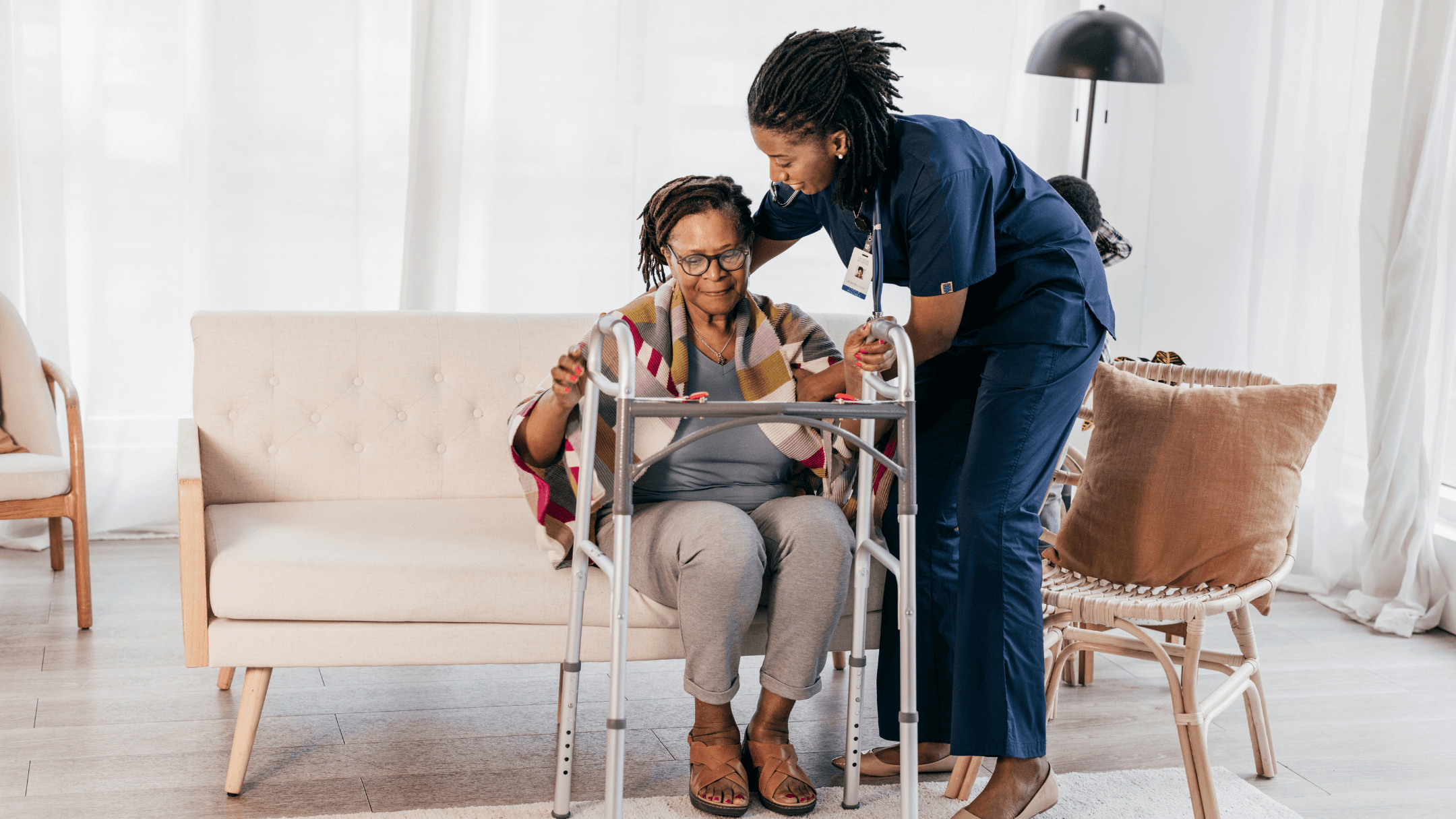 A caregiver steadying a senior woman as she stands with a walker