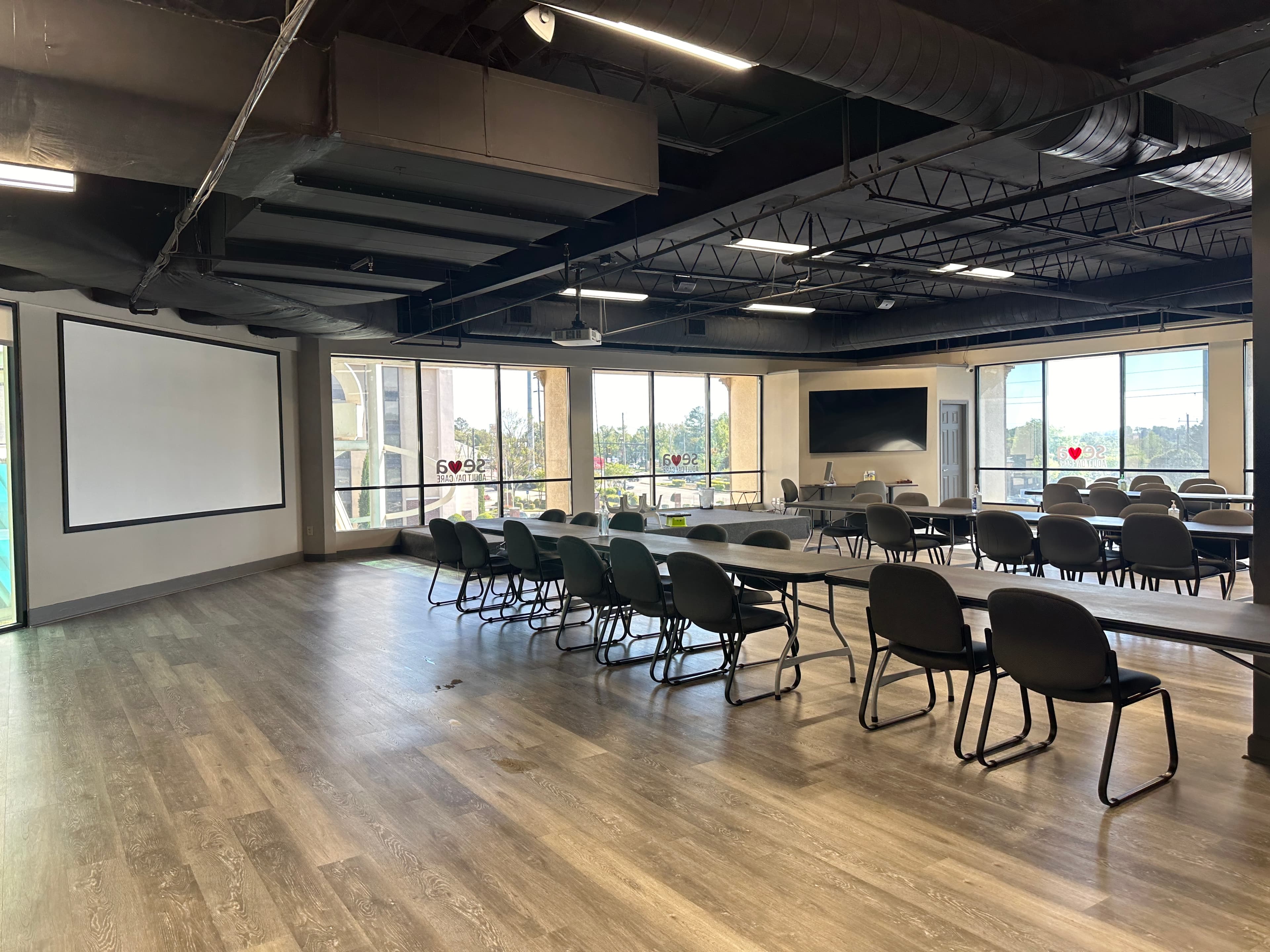 The large activity hall with long tables and a projector screen